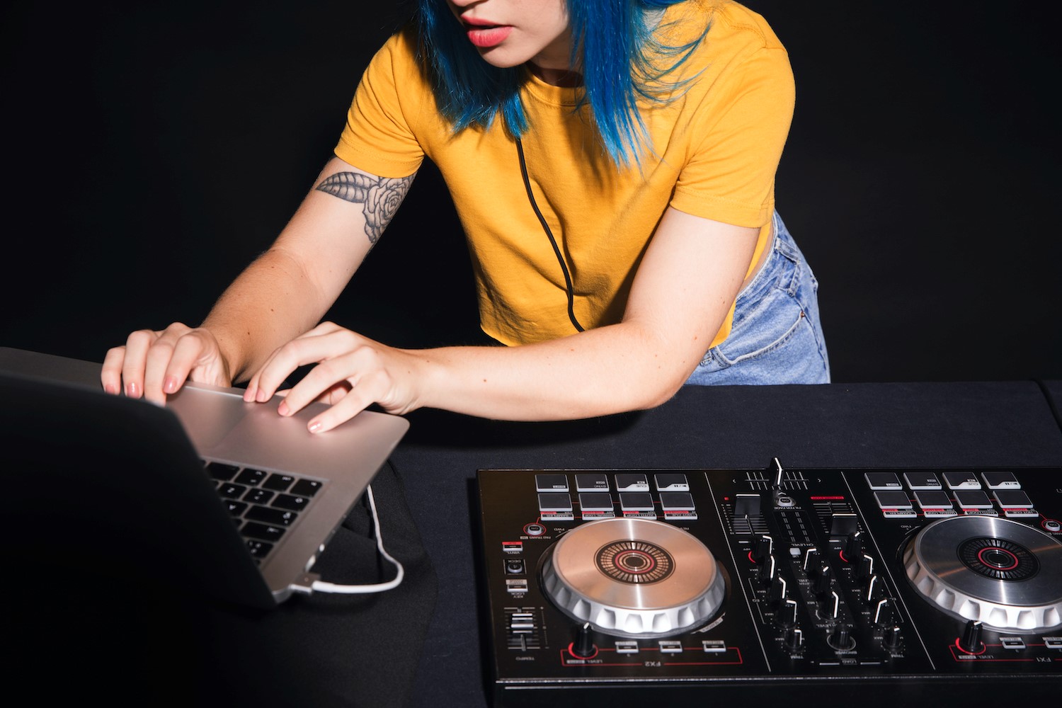Persoană care folosește un laptop lângă un controller DJ